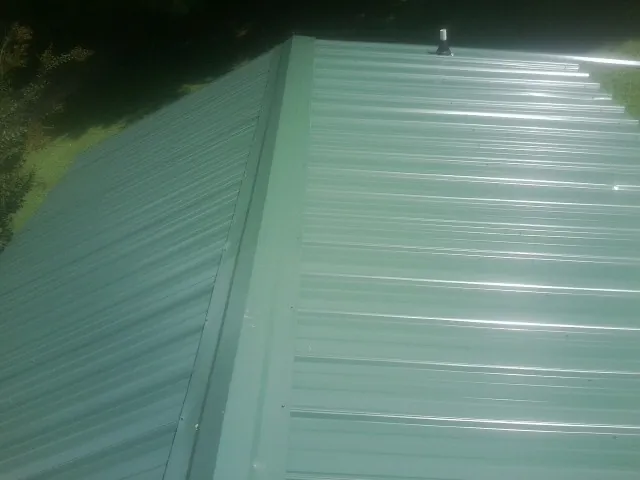 New green metal panels meeting at the ridge of a roof — Flat Roof Repair work by our crew in Redding
