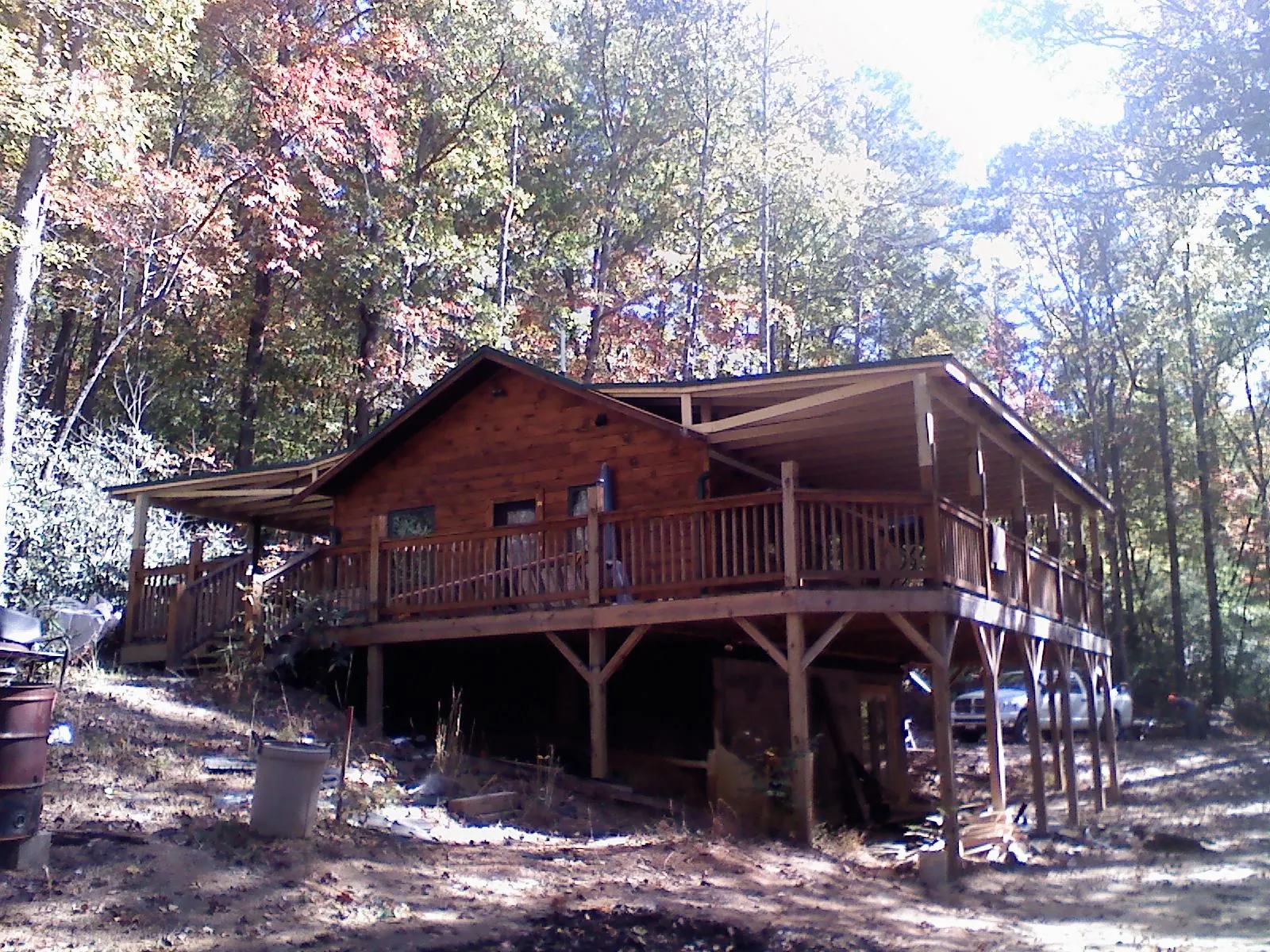Log cabin with a wraparound porch and metal roof in the fall in Redding