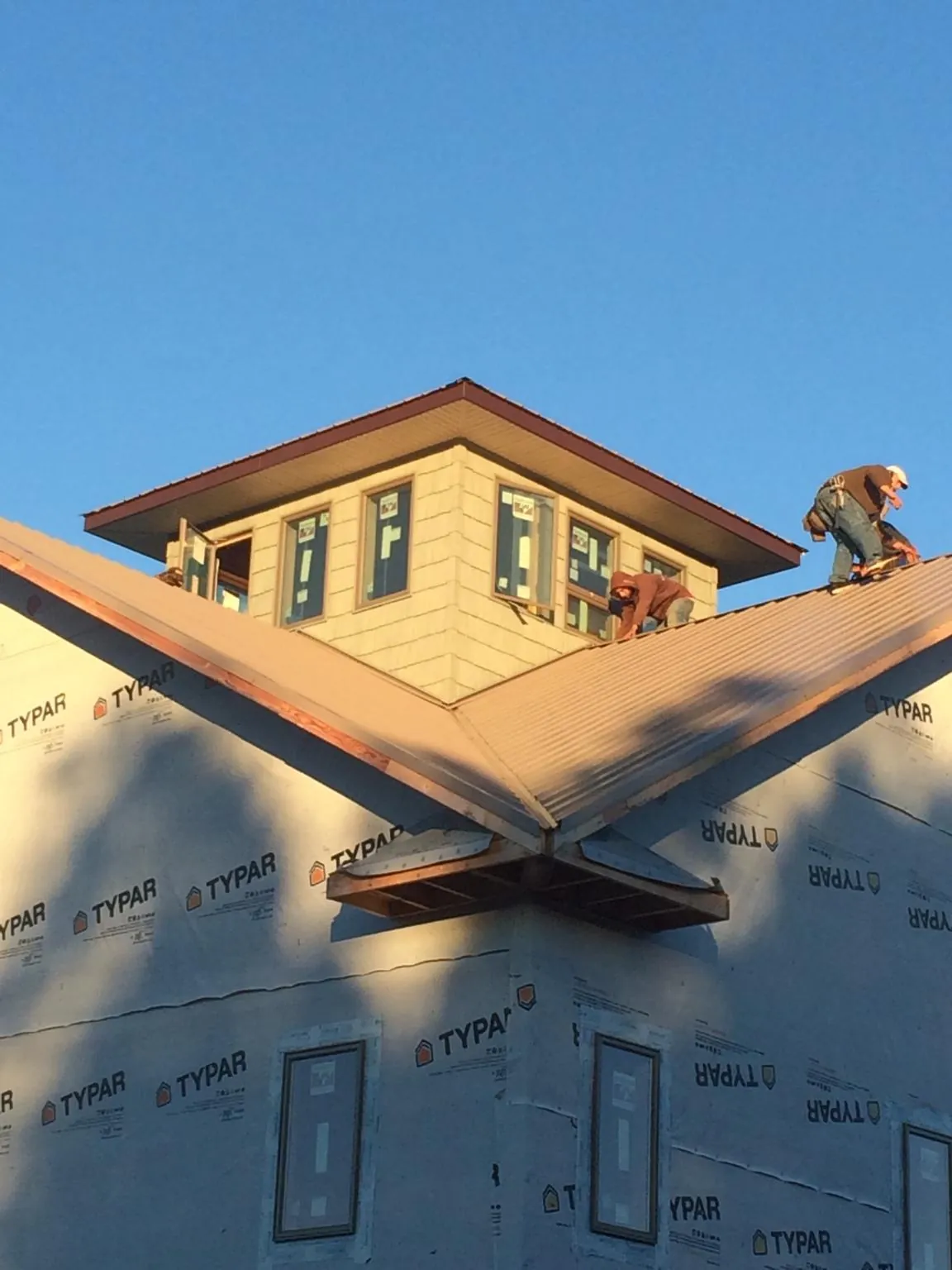 Roofers working around a rooftop cupola on a new metal roof at sunset — Roof Waterproofing in Redding by Roofing Brothers
